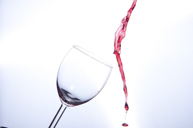 Rött vin som hälls bredvid ett vinglas